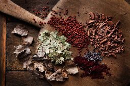 Various materials used to dye eggs laid out on old wooden board; dried birch leaves, cochineal, reddish seeds