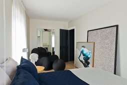 Doppelbett in modernem Schlafzimmer mit Sitzskulptur von Gaetano Pesce, großformatige moderne Bilder an Wand gelehnt