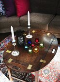 Teelichter in bunten Gläsern und Kerzenständer auf traditionellem Holztisch