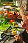 A girl eating tomatoes at a garden table in the summer