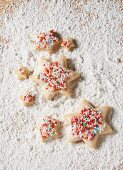 Sternplätzchen mit bunten Zuckerperlen auf gezuckertem Holzbrett