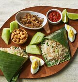 Coconut rice in banana leaves, eggs, fish, cucumber and dip (Asia)