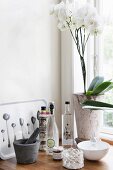 Pestle and mortar, vintage bottles and white orchid on windowsill