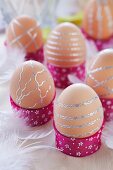 Brown eggs decorated with strips of silver stickers in hand-crafted egg cups