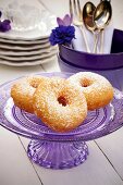 Donuts auf lilafarbenem Kuchenständer aus Glas
