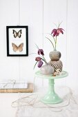 Snake's head fritillaries in small stoneware vases on cake stand made from pale green porcelain