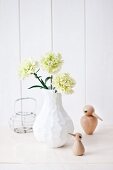 Green carnation in modern white vase and small bird ornaments