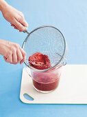 Raspberry purée being sieved
