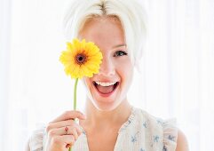 Portrait of blonde woman holding yellow flower