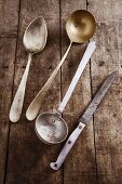 Old ladles, a spoon and a knife on a wooden surface