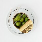 A tin of green olives and cocktail sticks