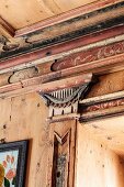 Kapitellornament auf Pilaster und florale Verzierungen als Teil der kunstvollen Holzvertäfelung in einem italienischen Chalet