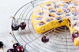 Cherry cake with icing sugar on a wire rack
