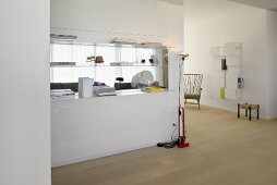 White partition with integrated shelves in spacious, bright interior; original wall-shelf and fifties armchair in background