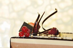 A three-layered chocolate cake topped with chocolate glaze and berries