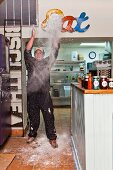 A chef in a restaurant throwing flour in the air