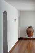 Amphora in metal frame against wall in empty room with arched doorway