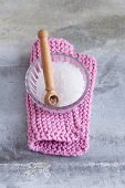 A bowl of salt and a wooden spoon on a knitted pot holder