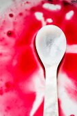 A mother-of-pearl spoon in red grape juice