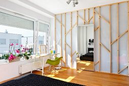 Sunny workspace with Eames Plastic Armchair below window in bedroom with mirrored door leading to dressing room