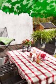 Tisch mit rot-weiss karierter Tischdecke und Outdoor-Stühle auf Terrasse
