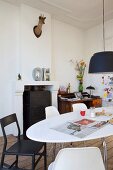 Black and white dining area with oval table, classic chairs, deer's head trophy on chimney breast and desk in background