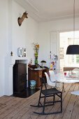 Deer's head trophy and alphabet ornaments on chimney breast in dining room with classic chairs and traditional writing desk in background