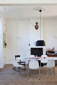 Black and white dining area with oval table and classic chairs in front of fireplace with deer's head on chimney breast