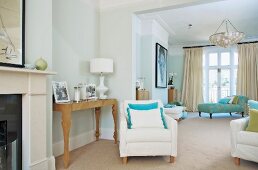 Pale armchair next to artistic console table and chaise longue in elegant living area