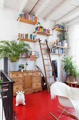 Red-painted wooden floor on gallery; wooden bookshelves on wall, classic rocking chair with white animal-skin rug