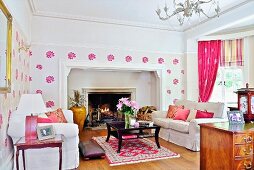 Living room with pink accents, white sofa set and black coffee table in front of open fireplace