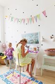 Two girls in bedroom with heart shaped stickers and bunting on wall