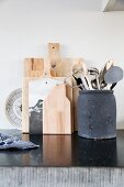 Kitchen utensils in clay container and wooden chopping boards