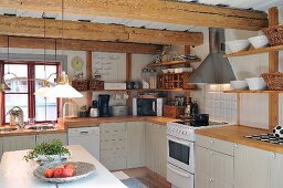 Skandinavische Landhausküche mit Holz-Küchenarbeitsplatte, Wandboards und rustikaler Holzbalkendecke mit Vintage Flair