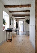Hallway in renovated wooden house with white wood cladding and ceiling beams
