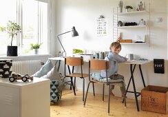 Boy's bedroom with desk, wall-mounted shelves, wooden chairs and vintage wooden crate