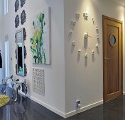 Clock, floral painting and mirror on double row of stylised flowers on outside corner in open-plan interior