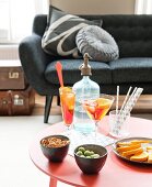 Cocktail glasses and bowl of snacks on red table