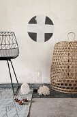 Detail of black metal chair and basket on various grey rugs below stencilled motif on wall