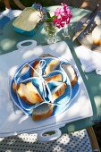 Brotkörbchen mit Fächern für Baguettescheiben und Servierplatte auf Frühstückstisch im Garten