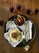 Brie topped with chopped nuts and rosemary served with fruit crisps red wine