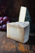 Hard cheese and grapes on a wooden surface