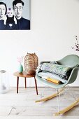 Classic rocking chair and lantern on table below picture on wall