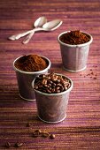 Verschiedene Kaffeearten: Kaffeebohnen, Pulver, Löskaffee in Metallbechern