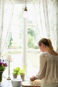 Woman baking rhubarb cake next to window in kitchen