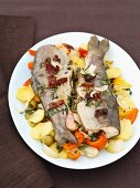Baked trout with herbs, butter and vegetables on a plate