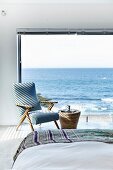 Ocean view from bed through panoramic windows and fifties-style armchair