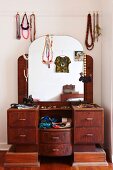Retro dressing table with arched mirror decorated with necklaces, silk scarves, jewellery and feminine accessories