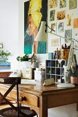 Old wooden desk below poster and postcards on wall