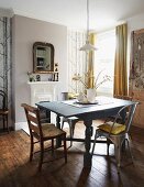 Wood and metal chairs around wooden table with turned legs painted pale grey in traditional dining room